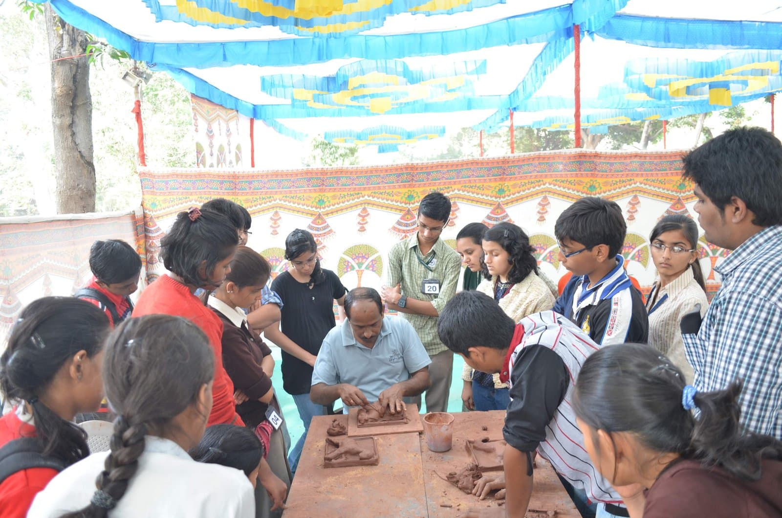 Dinesh Chandra Kumhar conducting a live terracotta clay plaque sculpting demonstration for school students