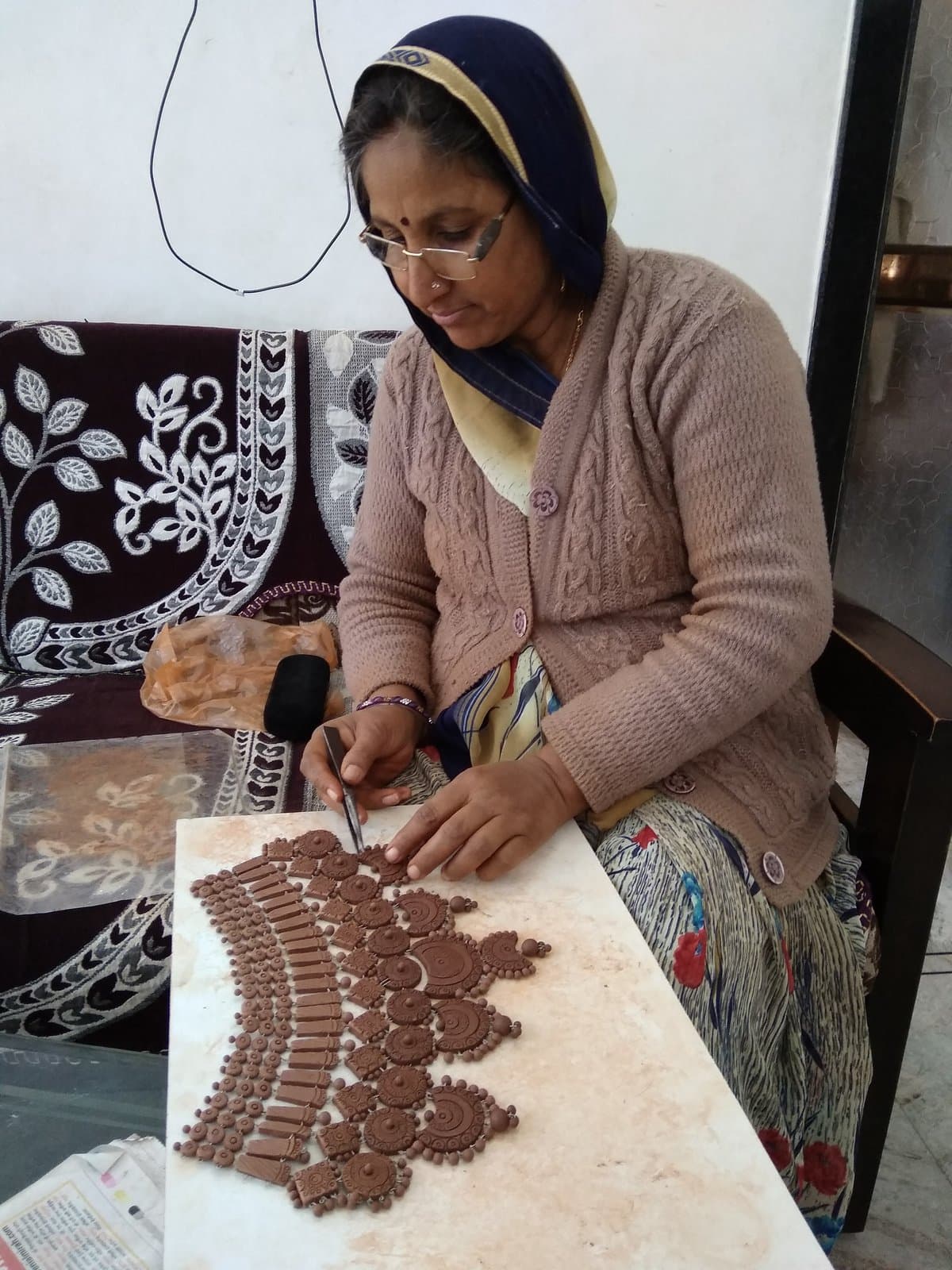 Kailash Devi meticulously sculpting an intricate royal terracotta collar necklace