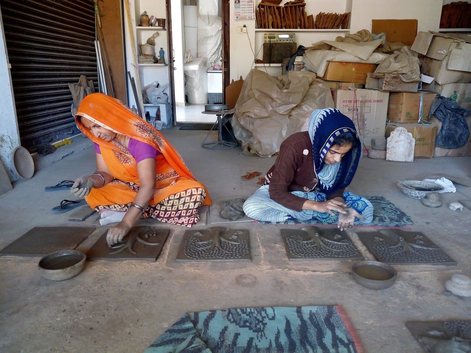 Kailash Devi and Sonali Prajapati hand-moulding tree-of-life terracotta relief panels in the workshop
