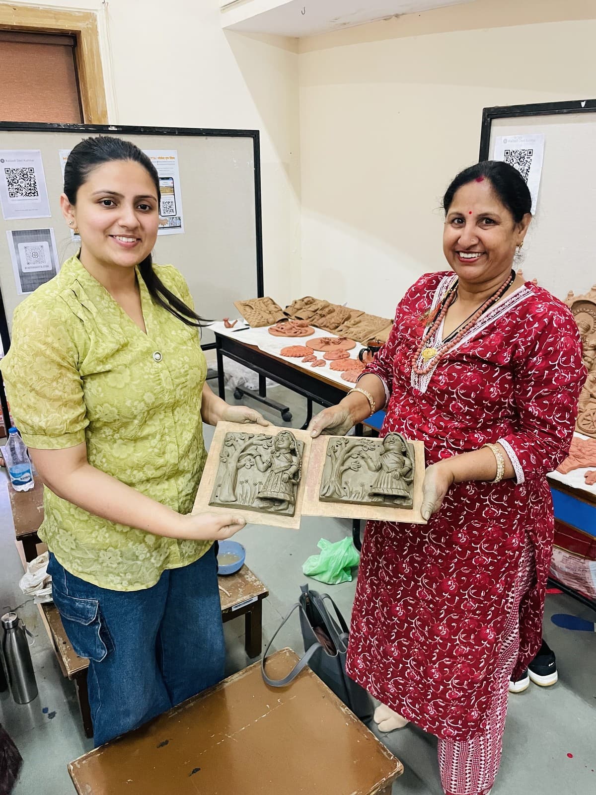 Kailash Devi mentoring a student and displaying newly sculpted wet clay narrative relief tiles