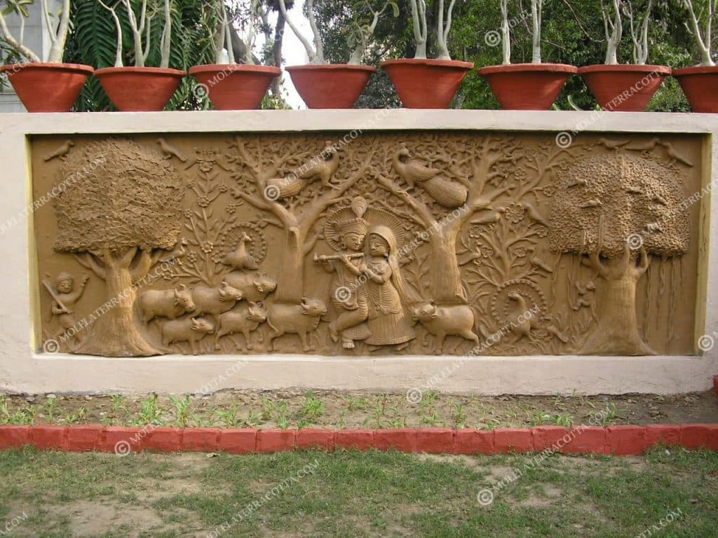 Custom outdoor terracotta wall mural of Krishna and Radha installed along a garden courtyard wall